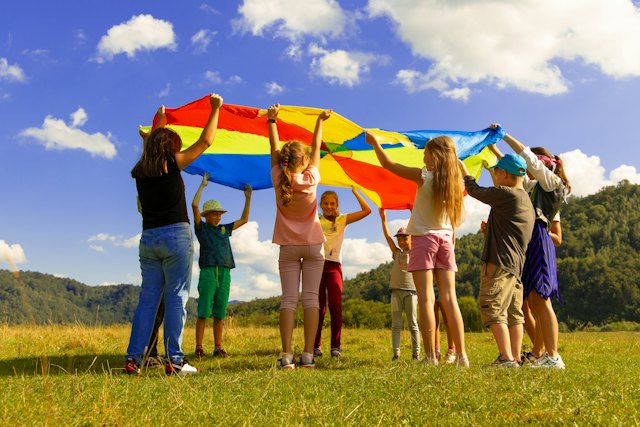 Kinderen spelen met een gekleurde parachute op het gras