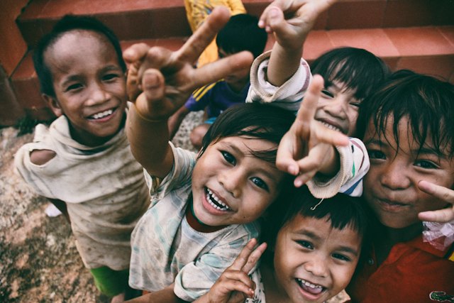 Vijf lachende kinderen maken een peace-teken